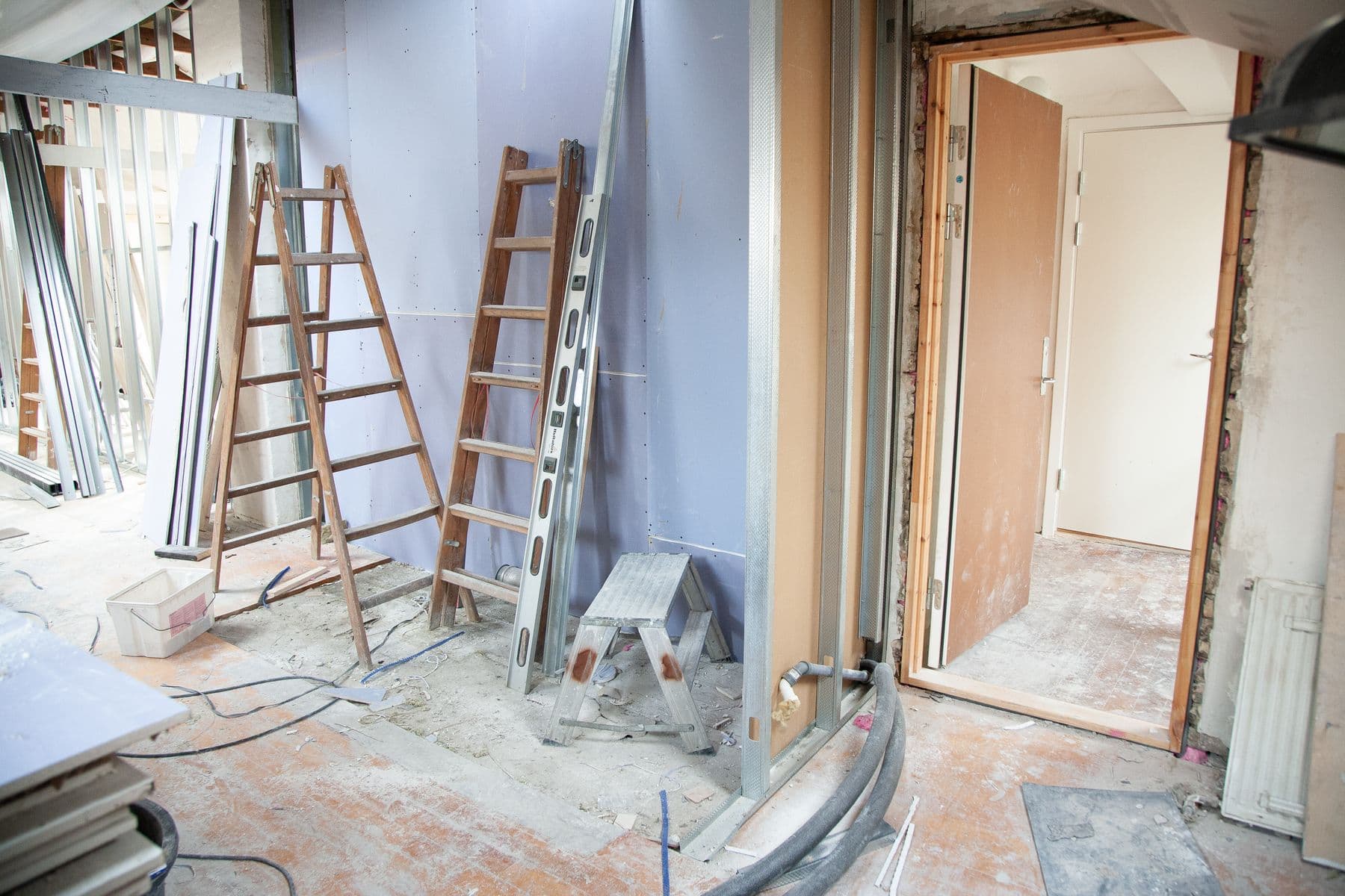 Rooms stripped to bare walls and floors, with stepladders, metal studs and an open door frame.